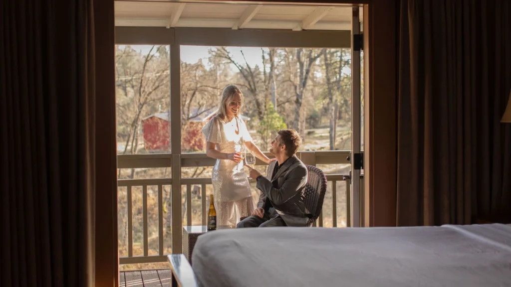 Guest relaxing on private veranda with French doors open to king bed room at Sierra Sky Ranch boutique hotel near Yosemite National Park