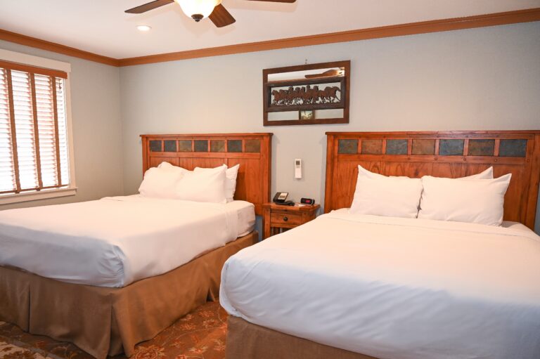 Spacious 475 sq ft two-room suite with two queen beds and decorative stone fireplace at Sierra Sky Ranch near Yosemite sleeps 6