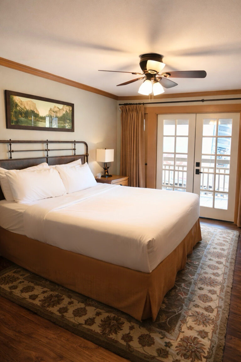 Ranch House king room with plush bed and French doors to veranda overlooking Great Lawn at Sierra Sky Ranch near Yosemite South Entrance