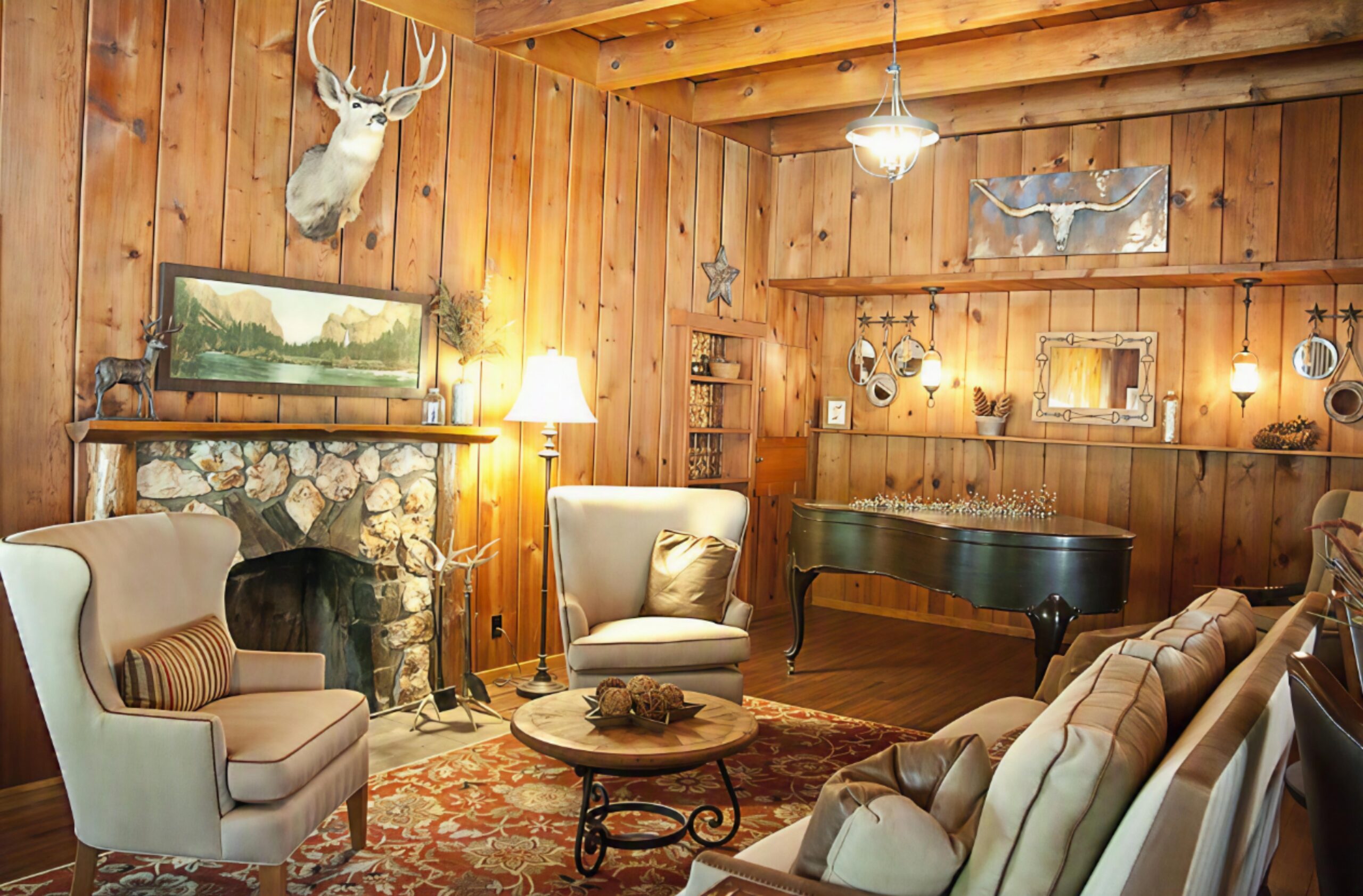 The Great Room at Sierra Sky Ranch, with its stone fireplace, grand piano, and seating under a beamed ceiling.